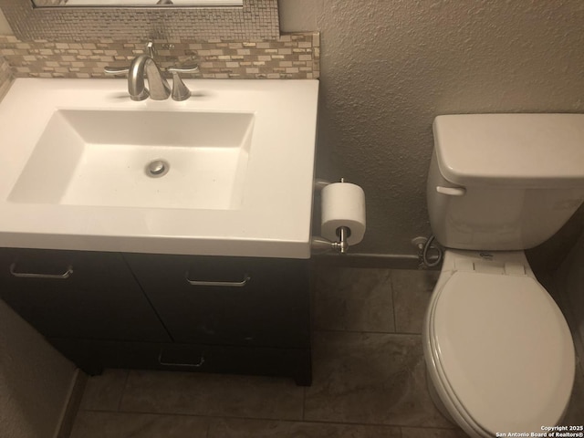 bathroom with toilet, tile patterned flooring, backsplash, and vanity