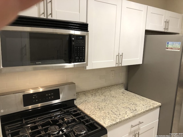 kitchen featuring white cabinetry, light stone counters, backsplash, and appliances with stainless steel finishes