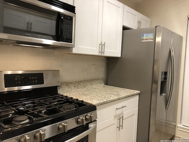 kitchen with light stone counters, white cabinetry, appliances with stainless steel finishes, and tasteful backsplash