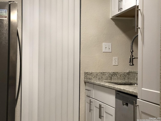 interior space featuring light stone counters, sink, white cabinets, and stainless steel appliances