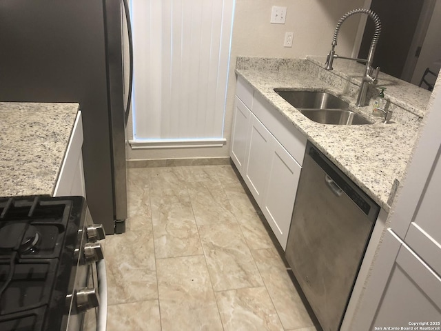 kitchen featuring stainless steel appliances, white cabinetry, light stone counters, and sink