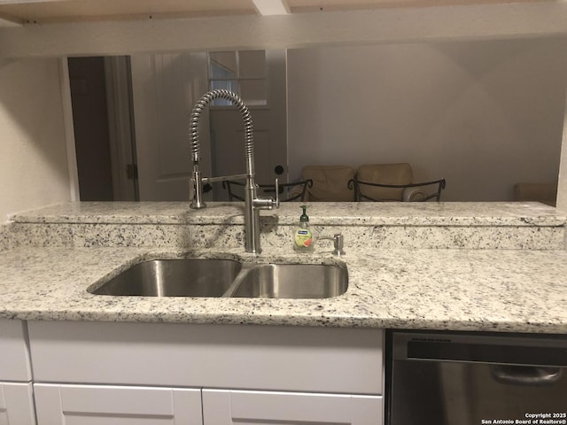 kitchen featuring light stone countertops, white cabinets, dishwasher, and sink