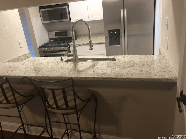 kitchen with white cabinets, sink, a kitchen breakfast bar, and stainless steel appliances