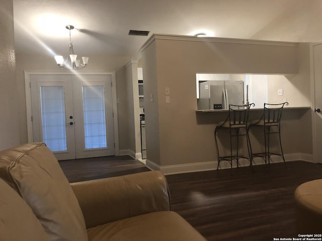 living room featuring dark wood-type flooring, french doors, and an inviting chandelier