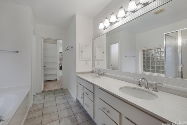 bathroom featuring tile patterned flooring, a tub to relax in, and vanity