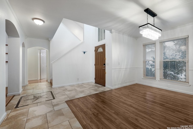 foyer with an inviting chandelier, light tile patterned floors, and crown molding