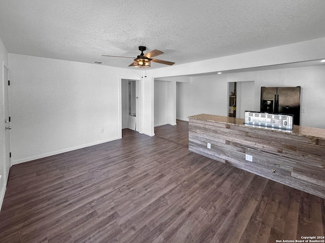 unfurnished living room featuring ceiling fan, dark wood-type flooring, and a textured ceiling