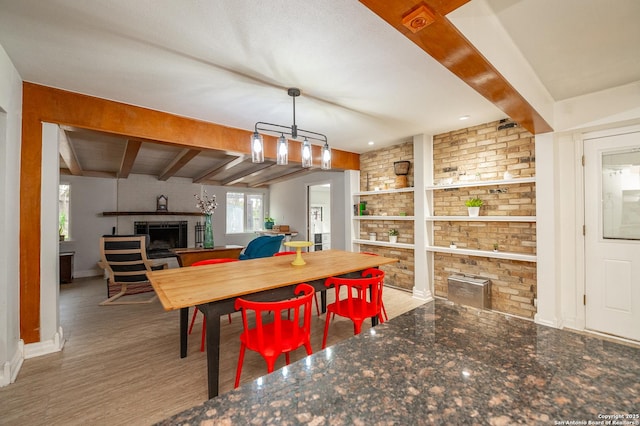 dining room featuring a brick fireplace, hardwood / wood-style flooring, and beamed ceiling