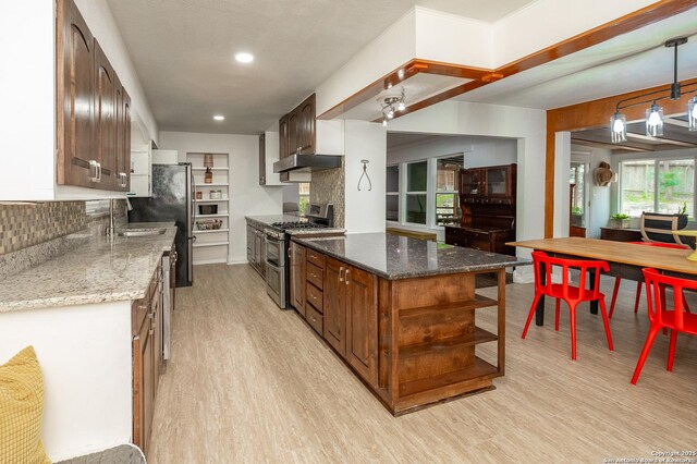 kitchen with light stone countertops, backsplash, stainless steel appliances, and light wood-type flooring