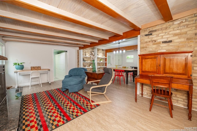 living room featuring a fireplace, beam ceiling, light hardwood / wood-style flooring, and an inviting chandelier