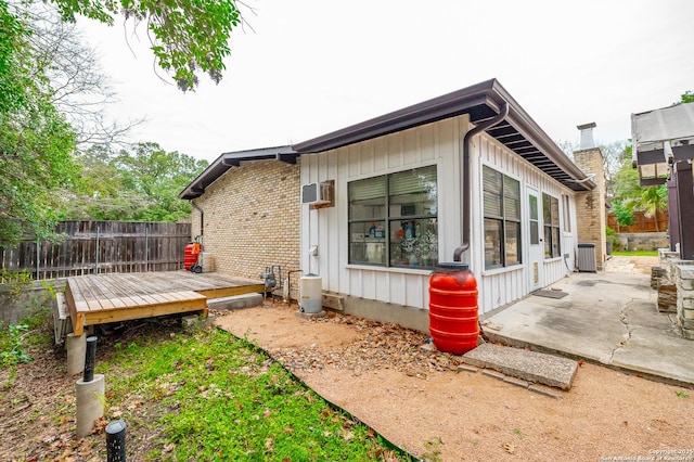 view of side of home with cooling unit, a patio, and a wooden deck