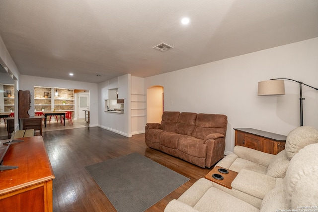 living room with dark wood-type flooring and built in shelves