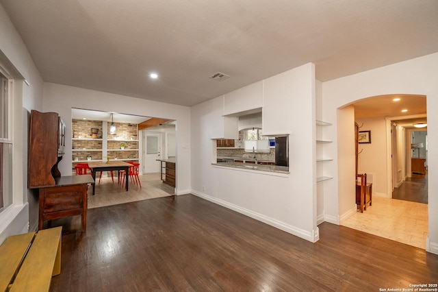 interior space with built in shelves, dark wood-type flooring, and a textured ceiling