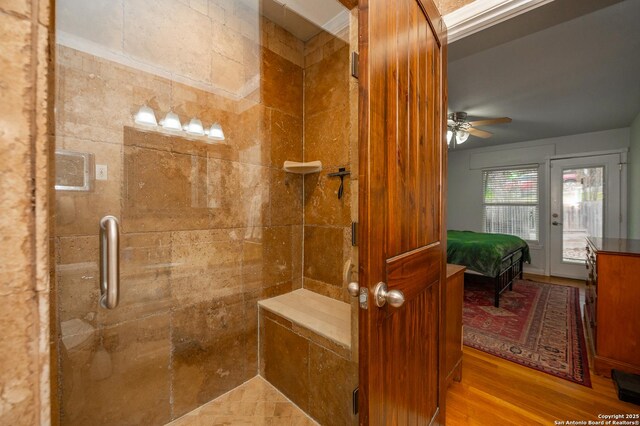 bathroom featuring ceiling fan, ornamental molding, and a shower with door