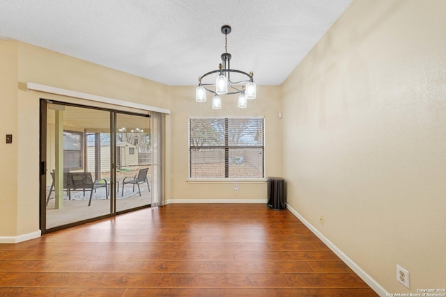 unfurnished dining area with dark wood-type flooring, plenty of natural light, and a chandelier