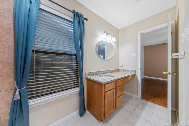 bathroom with a textured ceiling, tile patterned flooring, and vanity