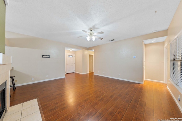 unfurnished living room featuring a textured ceiling, ceiling fan, a fireplace, and hardwood / wood-style flooring