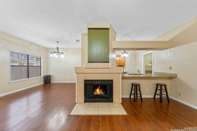 unfurnished living room featuring a chandelier, hardwood / wood-style flooring, a tile fireplace, and sink