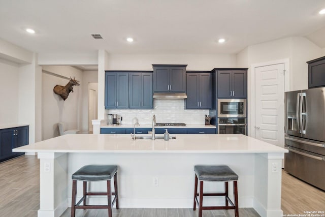 kitchen featuring appliances with stainless steel finishes, a large island with sink, and a kitchen bar