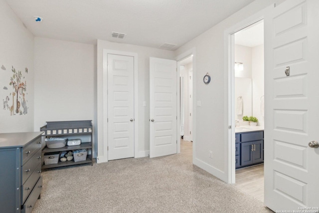 bedroom featuring light carpet and connected bathroom