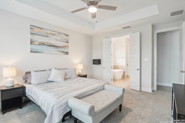 bedroom with a raised ceiling, ensuite bath, ceiling fan, and light colored carpet