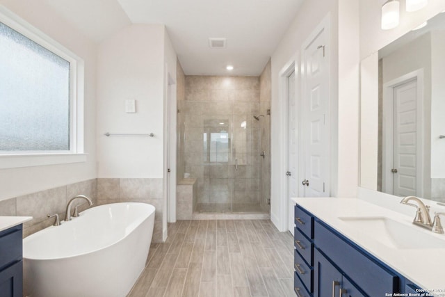 bathroom featuring tile walls, vanity, a wealth of natural light, and plus walk in shower