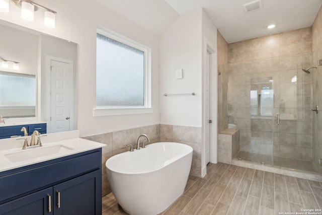 bathroom with tile walls, vanity, and independent shower and bath