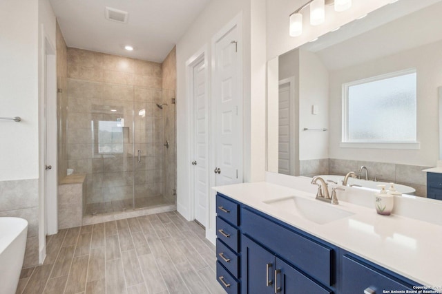 bathroom featuring hardwood / wood-style floors, tile walls, separate shower and tub, and vanity