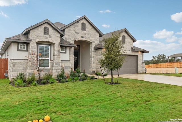 french country inspired facade featuring a front lawn and a garage