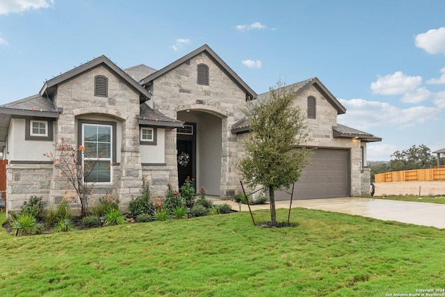 french country style house featuring a garage and a front lawn