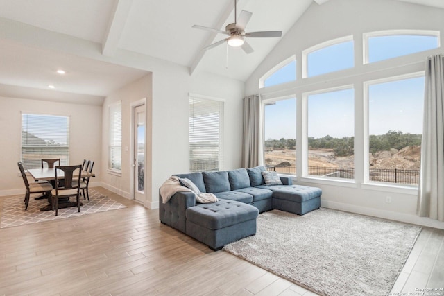 living room featuring beamed ceiling, a wealth of natural light, and light hardwood / wood-style flooring