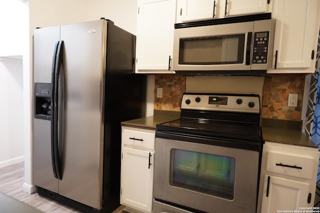 kitchen with appliances with stainless steel finishes, white cabinets, and tasteful backsplash