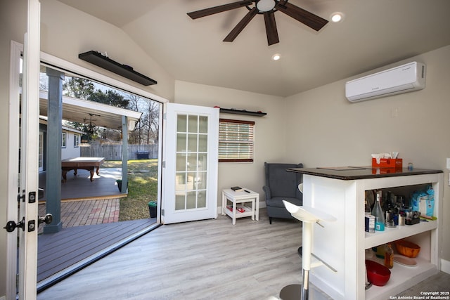 bedroom featuring an AC wall unit, light hardwood / wood-style flooring, french doors, and vaulted ceiling