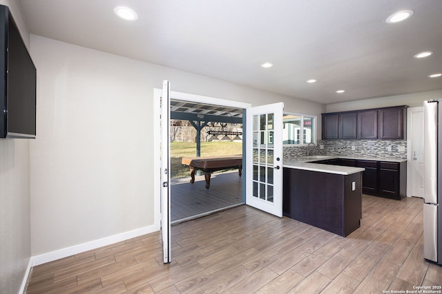 kitchen featuring light hardwood / wood-style floors, backsplash, and dark brown cabinetry