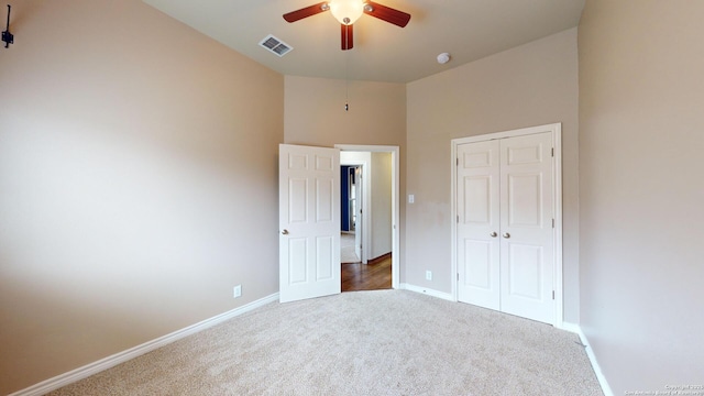 unfurnished bedroom featuring ceiling fan, dark carpet, and a closet