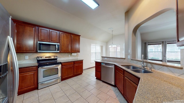 kitchen with appliances with stainless steel finishes, lofted ceiling, decorative light fixtures, tasteful backsplash, and sink