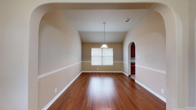 empty room with dark wood-type flooring and lofted ceiling