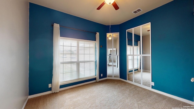 spare room with ceiling fan, a wealth of natural light, and carpet flooring