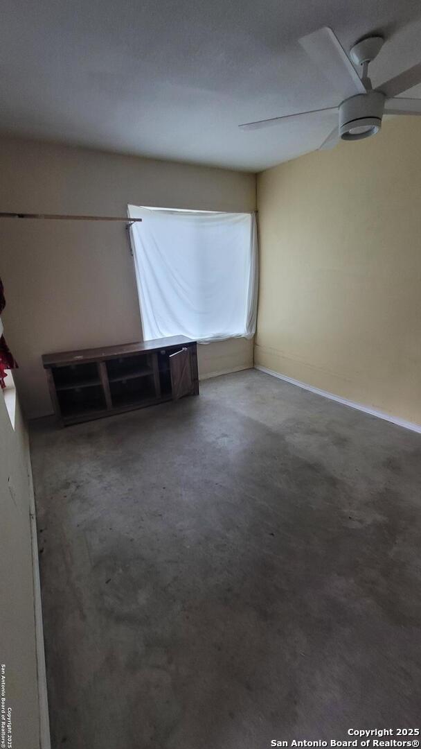 empty room featuring ceiling fan and concrete flooring