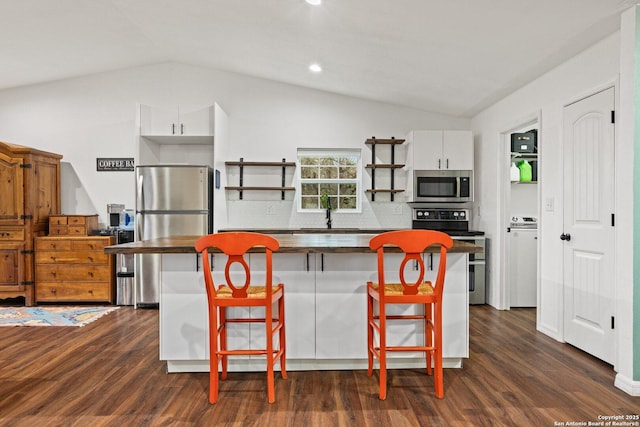 kitchen featuring decorative backsplash, white cabinetry, stainless steel appliances, and vaulted ceiling