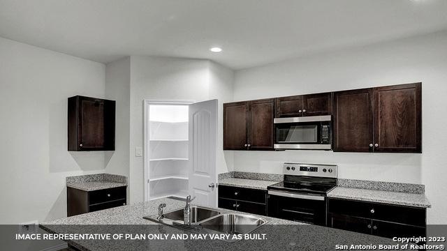 kitchen featuring appliances with stainless steel finishes, dark brown cabinets, and sink