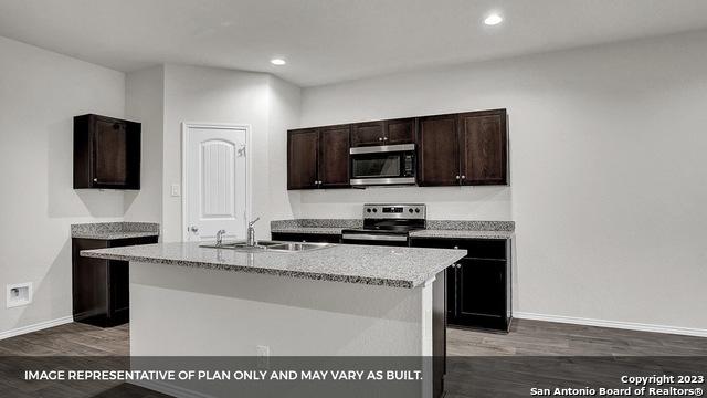 kitchen featuring dark wood-type flooring, sink, stainless steel appliances, and a center island with sink