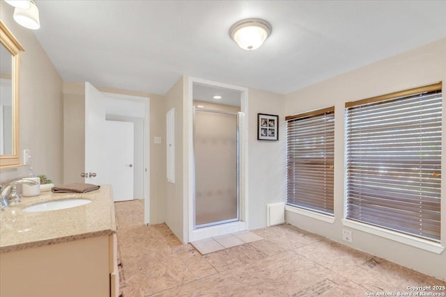 bathroom featuring a shower with door and vanity