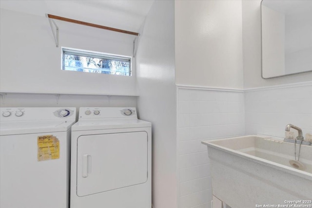 washroom featuring tile walls, sink, and washer and clothes dryer