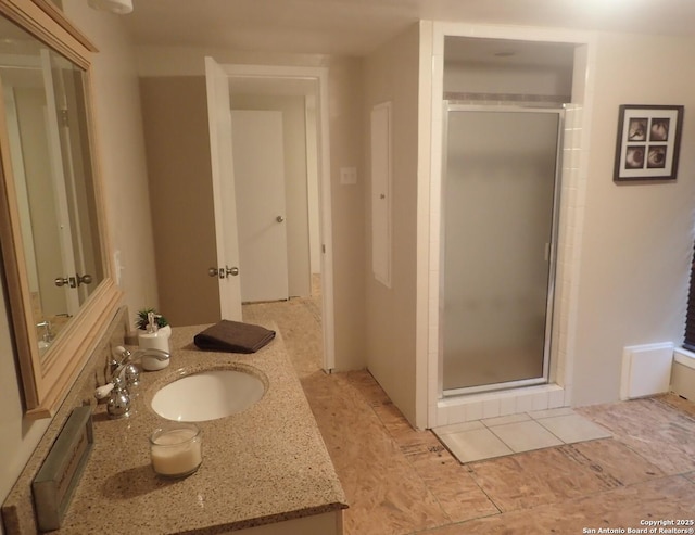 bathroom featuring a shower with door and vanity