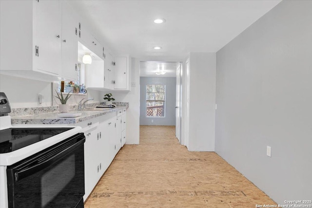 kitchen with white cabinetry, sink, and electric range