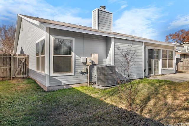 rear view of house featuring a lawn and central AC