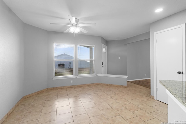 empty room with ceiling fan and light tile patterned floors