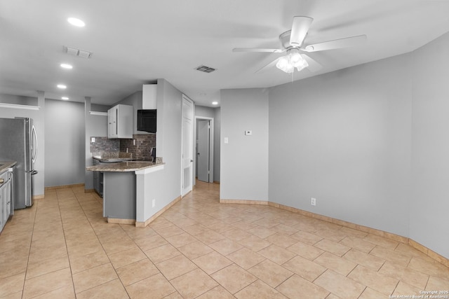 kitchen with light tile patterned floors, stainless steel fridge, ceiling fan, decorative backsplash, and white cabinets