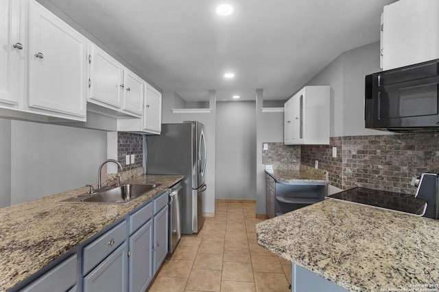 kitchen featuring light tile patterned floors, stainless steel dishwasher, white cabinets, light stone counters, and sink